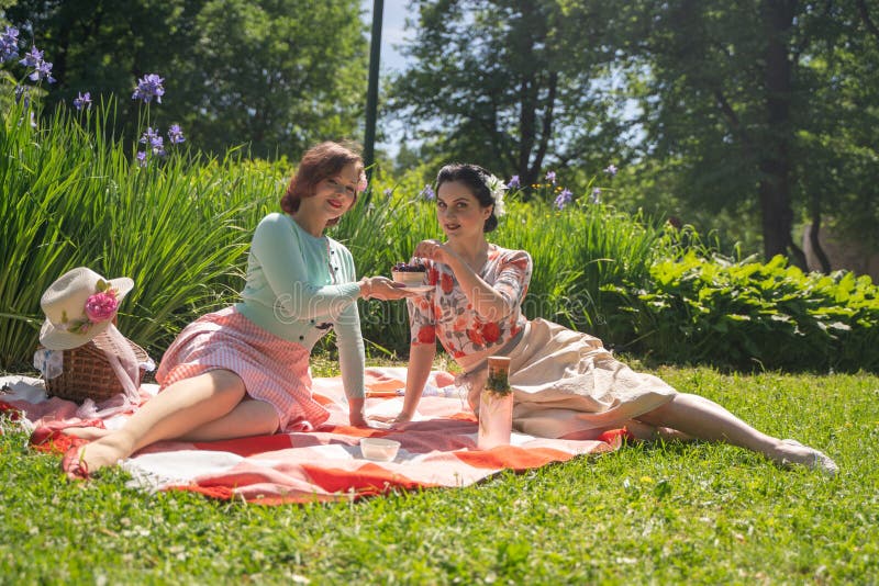 Parkerar nätt stift två upp damer som har den trevliga picknicken i staden, i en solig dag tillsammans flickavänner tycker om var royaltyfria bilder Parkerar nätt stift två upp damer som har den trevliga picknicken i staden, i en solig dag tillsammans flickavänner tycker om var royaltyfria bilder