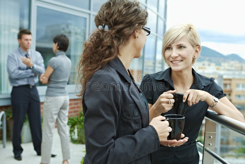 Businesswomen having break on office terrace outdoor drinking coffee talking. Businesswomen having break on office terrace outdoor drinking coffee talking.