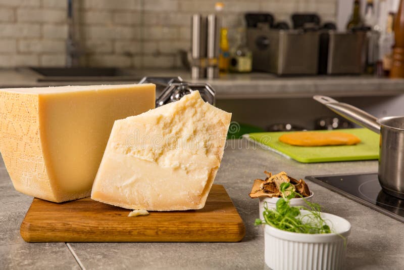 Parmigiano sul tagliere con basilico e coltello su fondo di legno fotografie stock Parmigiano sul tagliere con basilico e coltello su fondo di legno fotografie stock