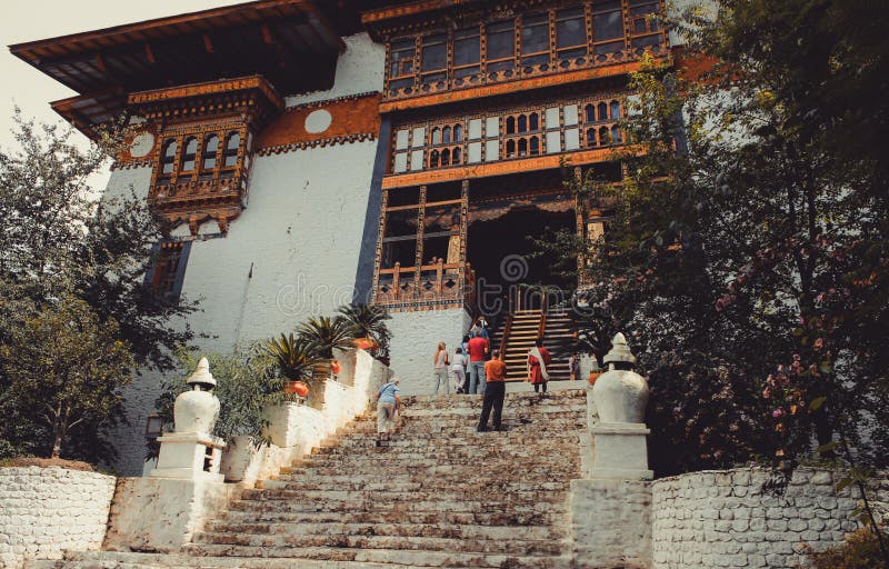 Paro, Butão - 10 de setembro de 2016: Opinião de baixo ângulo os turistas que estão em escadas de um templo velho foto de stock royalty free Paro, Butão - 10 de setembro de 2016: Opinião de baixo ângulo os turistas que estão em escadas de um templo velho foto de stock royalty free