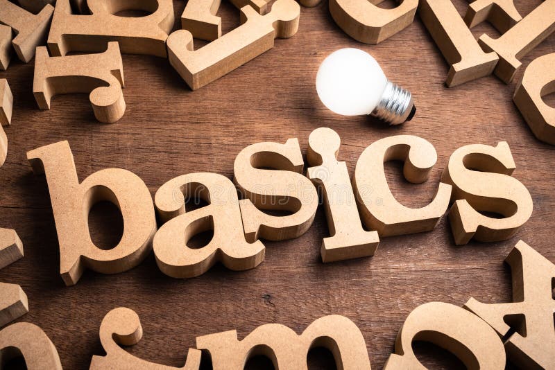 BASICS word in scattered wood letters on the table with glowing light bulb. BASICS word in scattered wood letters on the table with glowing light bulb