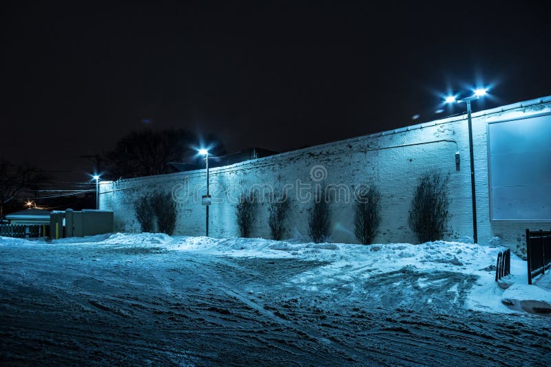 Parque de estacionamento escuro enchido neve da cidade na noite