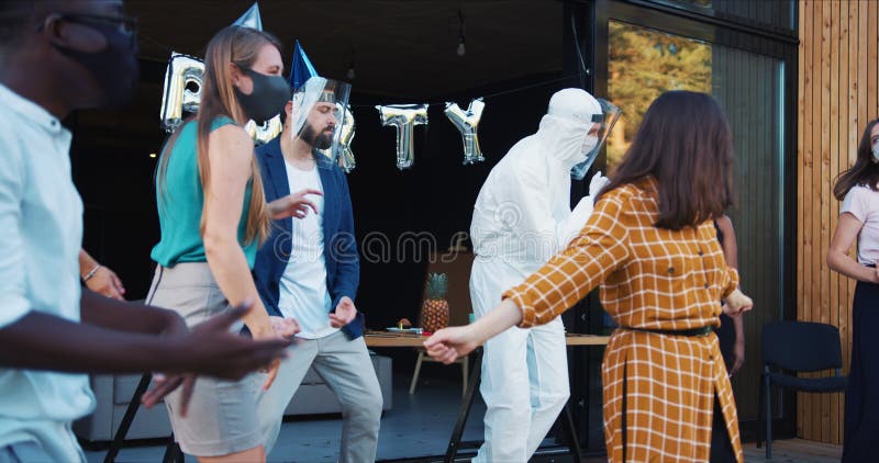 Part efter covid19 karantänslut. glada vänner dansar i dräkter och masker och firar tillsammans långsam rörelse. stock video