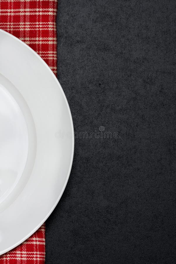 Part of the empty plate on a checkered napkin, black background