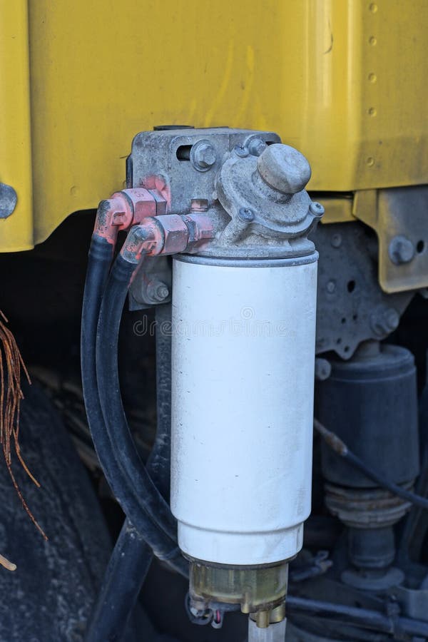 part of a truck with hoses on a white hydraulic metal cylinder on the street. part of a truck with hoses on a white hydraulic metal cylinder on the street