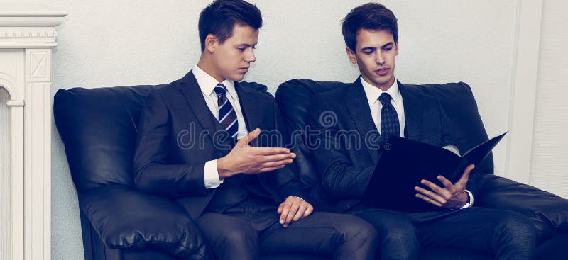 Parteneri de afaceri care discută documentele care stau pe canapea în sala de reuniune stock image