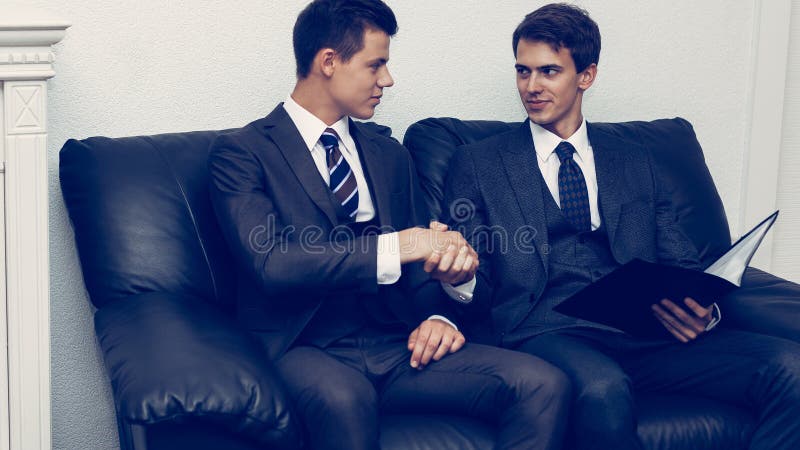 Parteneri de afaceri strângând mâna pe canapea royalty free stock photo