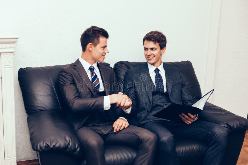 Parteneri de afaceri strângând mâna pe canapea royalty free stock images