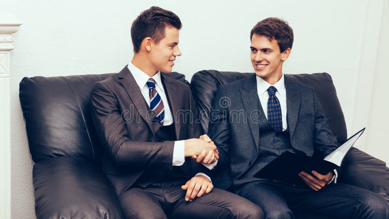 Parteneri de afaceri strângând mâna pe canapea stock images