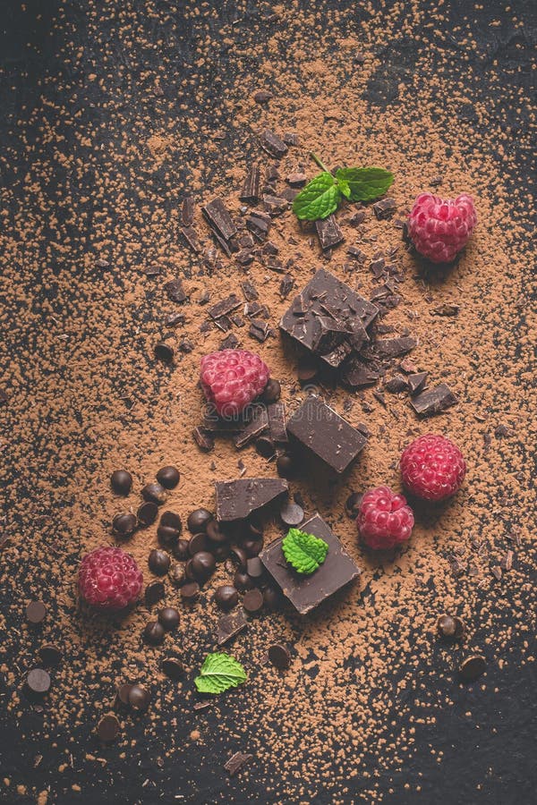 Partes de chocolate, de pó, de gotas e de framboesas escuros Fundo da sobremesa do alimento foto de stock Partes de chocolate, de pó, de gotas e de framboesas escuros Fundo da sobremesa do alimento foto de stock