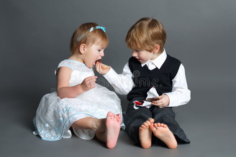 Partes do menino com a barra de chocolate da menina imagens de stock Partes do menino com a barra de chocolate da menina imagens de stock