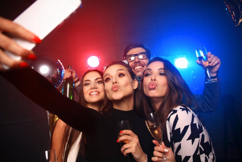 Parti, teknologi, uteliv och folkbegrepp - le vänner med smartphonen som tar selfie i klubba