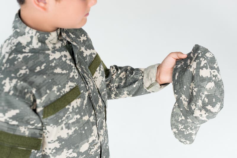 partial view of kid in military uniform holding camouflage cap stock photos partial view of kid in military uniform holding camouflage cap stock photos