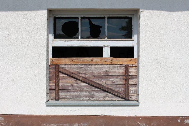Partially boarded window with broken glass and dilapidated wooden frame at abandoned building of old military complex royalty free stock images