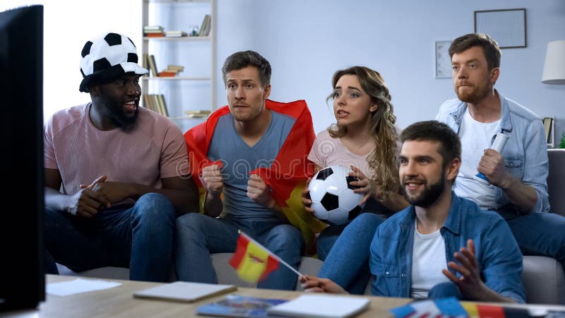 Partido de observación de los amigos españoles en la TV en casa, apoyando al equipo, unidad imagen de archivo libre de regalías Partido de observación de los amigos españoles en la TV en casa, apoyando al equipo, unidad imagen de archivo libre de regalías