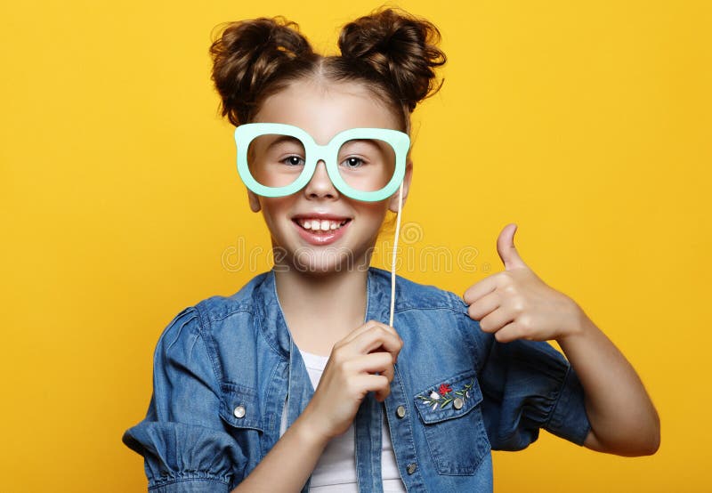 Partido, infância e conceito dos povos: menina com acessórios de papel sobre o fundo amarelo imagem de stock Partido, infância e conceito dos povos: menina com acessórios de papel sobre o fundo amarelo imagem de stock