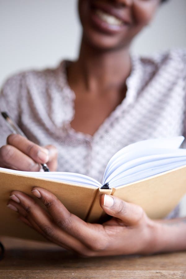 Partisk stående av att le hemmastadd handstil för svart kvinnlig författare i anteckningsbok