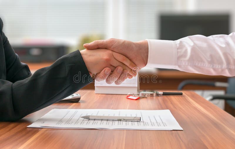Partnership concept. Businessman and woman sitting behind desk with agreement royalty free stock image Partnership concept. Businessman and woman sitting behind desk with agreement royalty free stock image