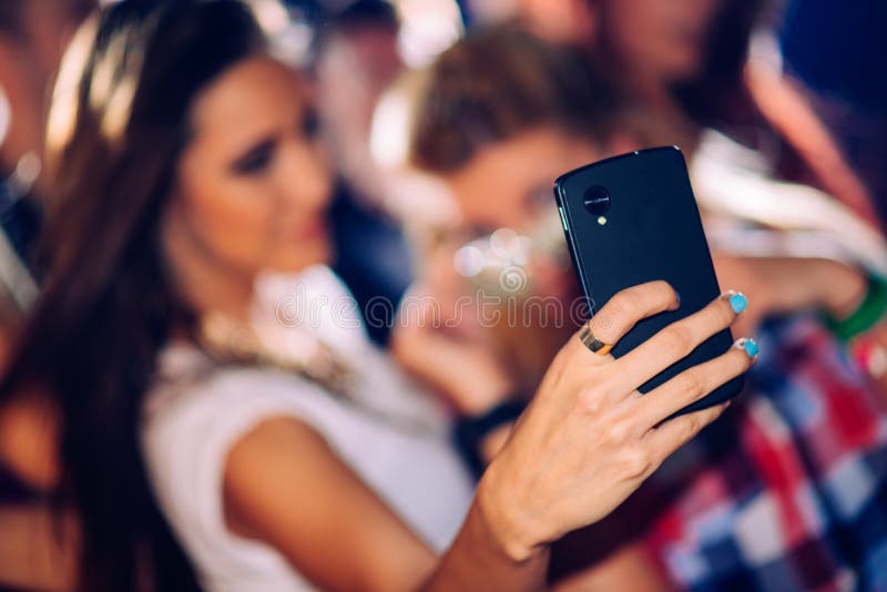 party, technology, nightlife and people concept - smiling friends with  smartphone taking selfie in club. Stock Photo