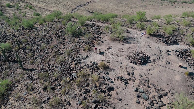 Pas de drone tournant autour du drapeau américain sur un pic rocheux séché banque de vidéos