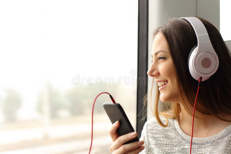 Pasajero adolescente que escucha la música que viaja en un tren Pasajero adolescente que escucha la música que viaja en un tren
