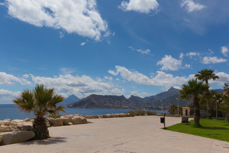 Paseo Calpe Испании на ноге утеса ориентира Penon de Ifach с взглядом гор стоковое изображение