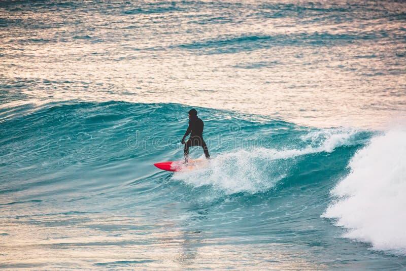 Paseo de la persona que practica surf en la tabla hawaiana roja en onda azul Invierno que practica surf en el océano fotos de archivo Paseo de la persona que practica surf en la tabla hawaiana roja en onda azul Invierno que practica surf en el océano fotos de archivo