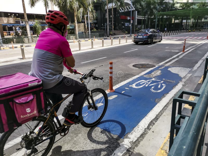 Pasig, Metro Manila, Philippines - April 2021: A Foodpanda deliveryman uses the designated bike lane in the business district