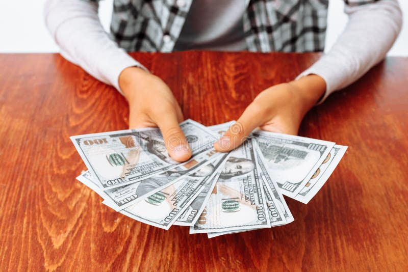Passa il primo piano che tiene molte cento banconote in dollari, sui precedenti di una tavola di legno, i soldi guadagnati immagini stock Passa il primo piano che tiene molte cento banconote in dollari, sui precedenti di una tavola di legno, i soldi guadagnati immagini stock