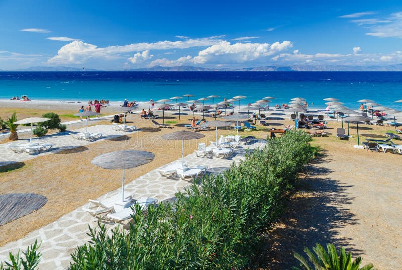 Passage couvert en bois blanc sur la plage comprenant des parapluies avec des chaises de plate-forme Mer Égée La Grèce Rhodes Cai images stock Passage couvert en bois blanc sur la plage comprenant des parapluies avec des chaises de plate-forme Mer Égée La Grèce Rhodes Cai images stock