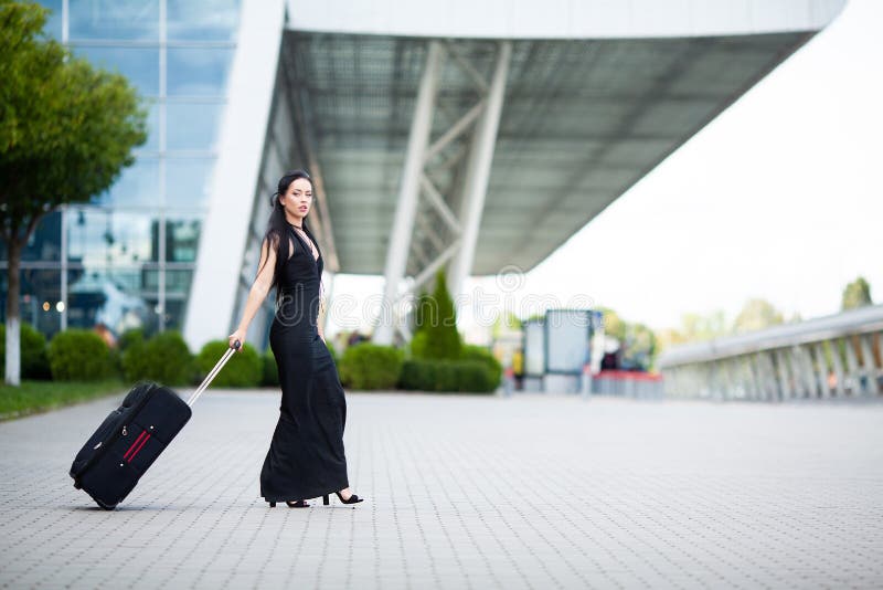 Smiling female passenger proceeding pulling suitcase through airport. Smiling female passenger proceeding pulling suitcase through airport.