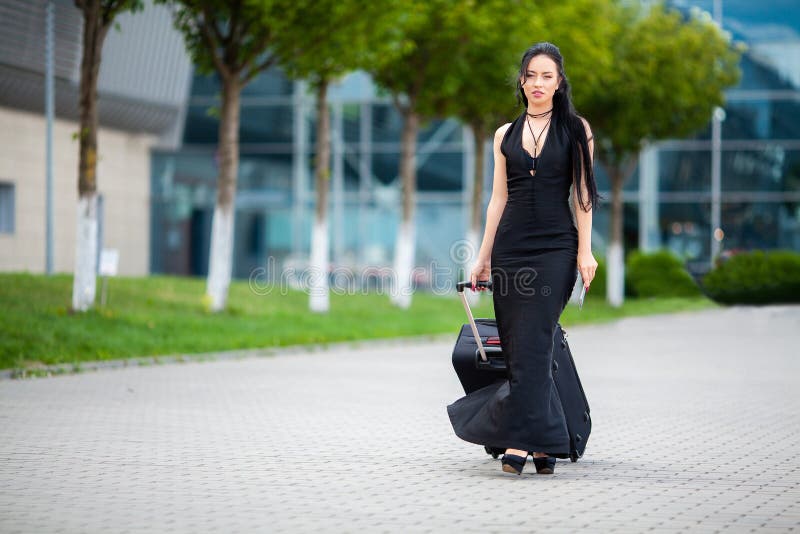 Smiling female passenger proceeding pulling suitcase through airport. Smiling female passenger proceeding pulling suitcase through airport.