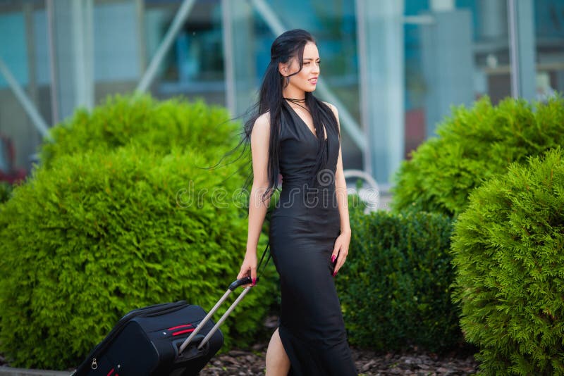 Smiling female passenger proceeding pulling suitcase through airport. Smiling female passenger proceeding pulling suitcase through airport.