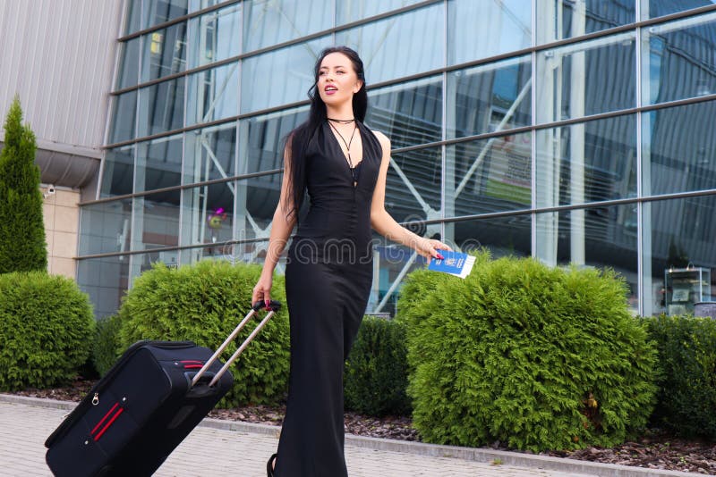 Smiling female passenger proceeding pulling suitcase through airport. Smiling female passenger proceeding pulling suitcase through airport.