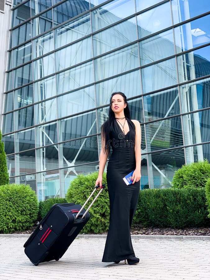 Smiling female passenger proceeding pulling suitcase through airport. Smiling female passenger proceeding pulling suitcase through airport.