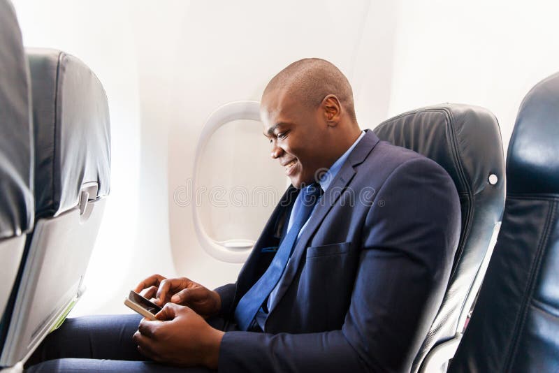 Happy african airplane passenger using smart phone on plane. Happy african airplane passenger using smart phone on plane