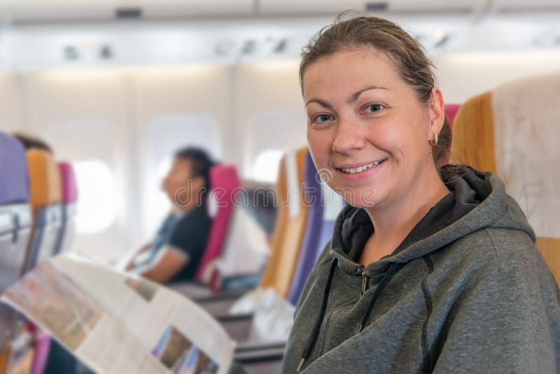 Passager heureux d'avion avec la magazine dans la chaise souriant pendant le f image libre de droits Passager heureux d'avion avec la magazine dans la chaise souriant pendant le f image libre de droits