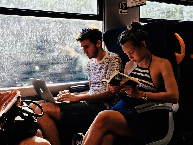 Passagerare för ung man och flickapå drevet som läser en bok arkivfoton Passagerare för ung man och flickapå drevet som läser en bok arkivfoton