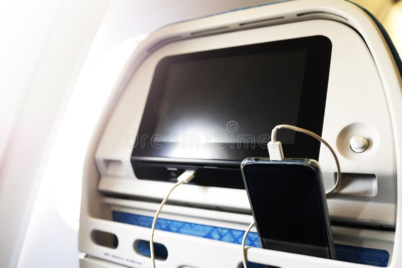 Passagerare på en nivå genom att använda uppladdaren för smart telefon för laddning under flyg Uppladdningsstation på nivån royaltyfri bild Passagerare på en nivå genom att använda uppladdaren för smart telefon för laddning under flyg Uppladdningsstation på nivån royaltyfri bild