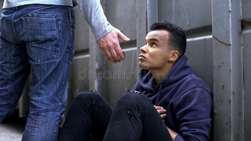 Passando dalla mano amica d'offerta dell'uomo al bambino di strada, alla gentilezza ed alla carità fotografia stock Passando dalla mano amica d'offerta dell'uomo al bambino di strada, alla gentilezza ed alla carità fotografia stock
