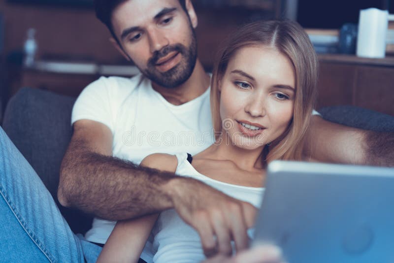 Passant le temps gentil à la maison Beaux jeunes couples affectueux collant entre eux et souriant tandis que femme tenant un livr photographie stock