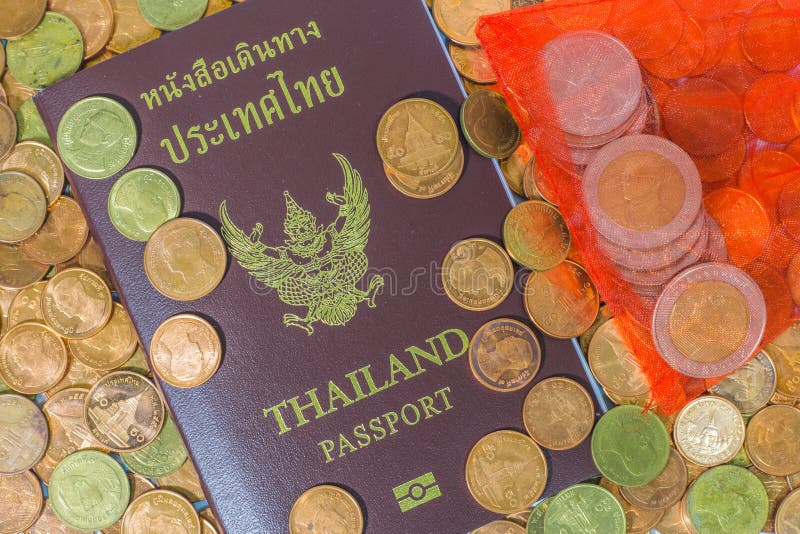 Passaporto tailandese su un mucchio delle monete immagine stock Passaporto tailandese su un mucchio delle monete immagine stock