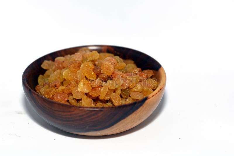 Dried raisins in a brown wooden bowl isolated on a white background, Iranian raisins, A raisin is a dried grape. Raisins are produced in many regions of the world and may be eaten raw or used in cooking, baking, and brewing. In the United Kingdom, Ireland, New Zealand, and Australia, the word raisin is reserved for the dark-colored dried large grape, with sultana being a golden-colored dried grape, and currant being a dried small Black Corinth seedless grape. Dried raisins in a brown wooden bowl isolated on a white background, Iranian raisins, A raisin is a dried grape. Raisins are produced in many regions of the world and may be eaten raw or used in cooking, baking, and brewing. In the United Kingdom, Ireland, New Zealand, and Australia, the word raisin is reserved for the dark-colored dried large grape, with sultana being a golden-colored dried grape, and currant being a dried small Black Corinth seedless grape.