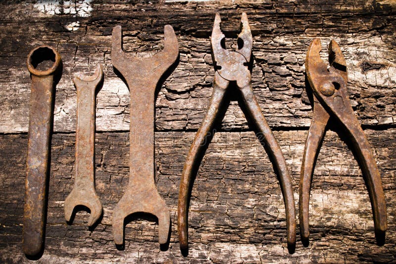 Passe as ferramentas oxidadas que trabalham em um de madeira velho