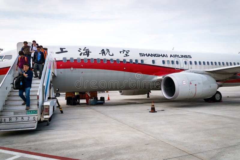 Passeggero che imbarca fuori da un aereo di Shanghai Airlines immagini stock Passeggero che imbarca fuori da un aereo di Shanghai Airlines immagini stock