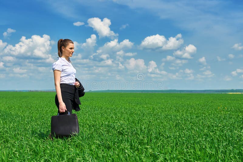 Passeggiata della donna di affari sul campo di erba verde all'aperto La bella ragazza si è vestita in vestito, il paesaggio della fotografia stock libera da diritti Passeggiata della donna di affari sul campo di erba verde all'aperto La bella ragazza si è vestita in vestito, il paesaggio della fotografia stock libera da diritti