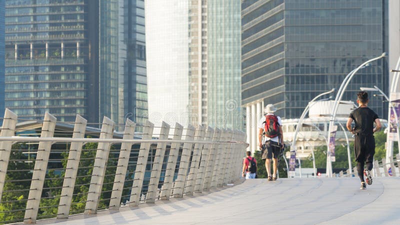 Passeggiata turistica in ponte pedonale della città con buil moderno esteriore immagine stock Passeggiata turistica in ponte pedonale della città con buil moderno esteriore immagine stock