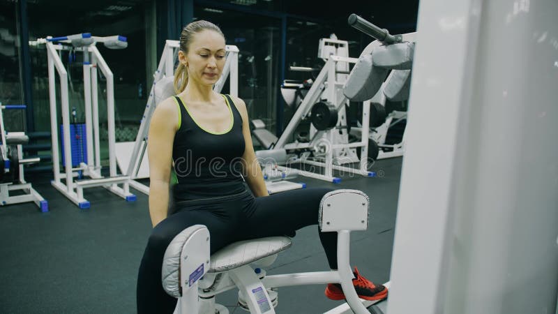 Passend atletisch meisje werkt in de dikke dijmachine met adductie en doet haar fitness - oefening. opleiding van musculair vrouwe