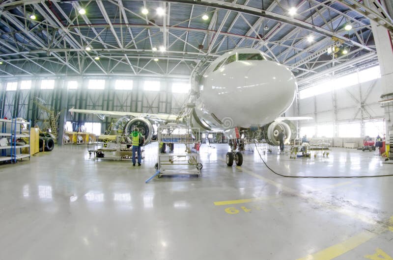 Passenger airplane on maintenance of engine, fuselage repair in airport hangar.