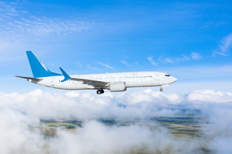 Passenger plane with landing gear lowered before boarding at the airport on a background of clouds and blue sky